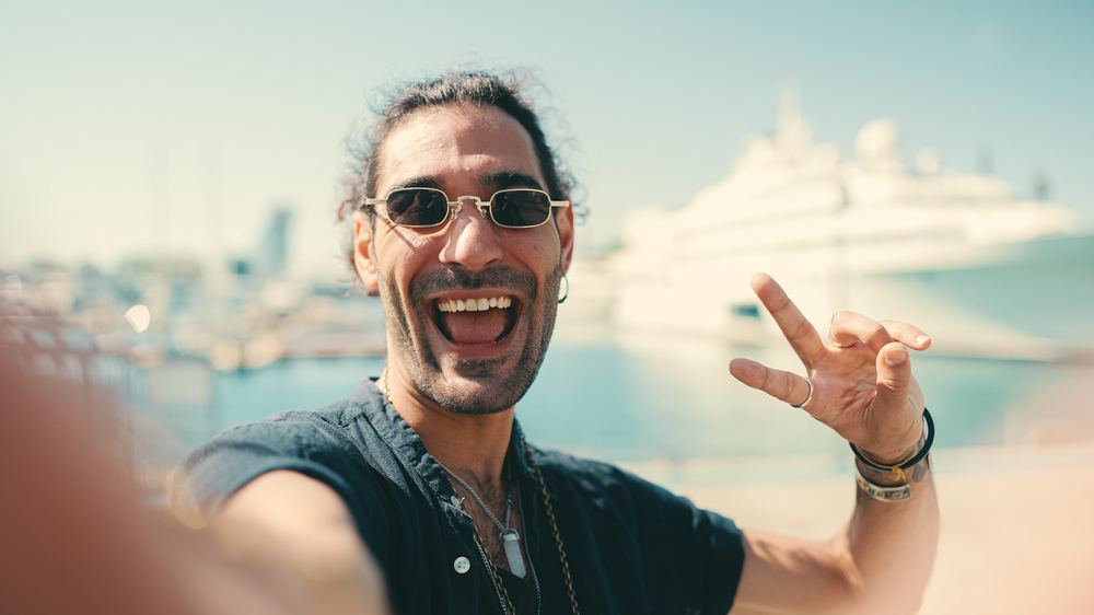 A man giving a playful peace sign near a marina